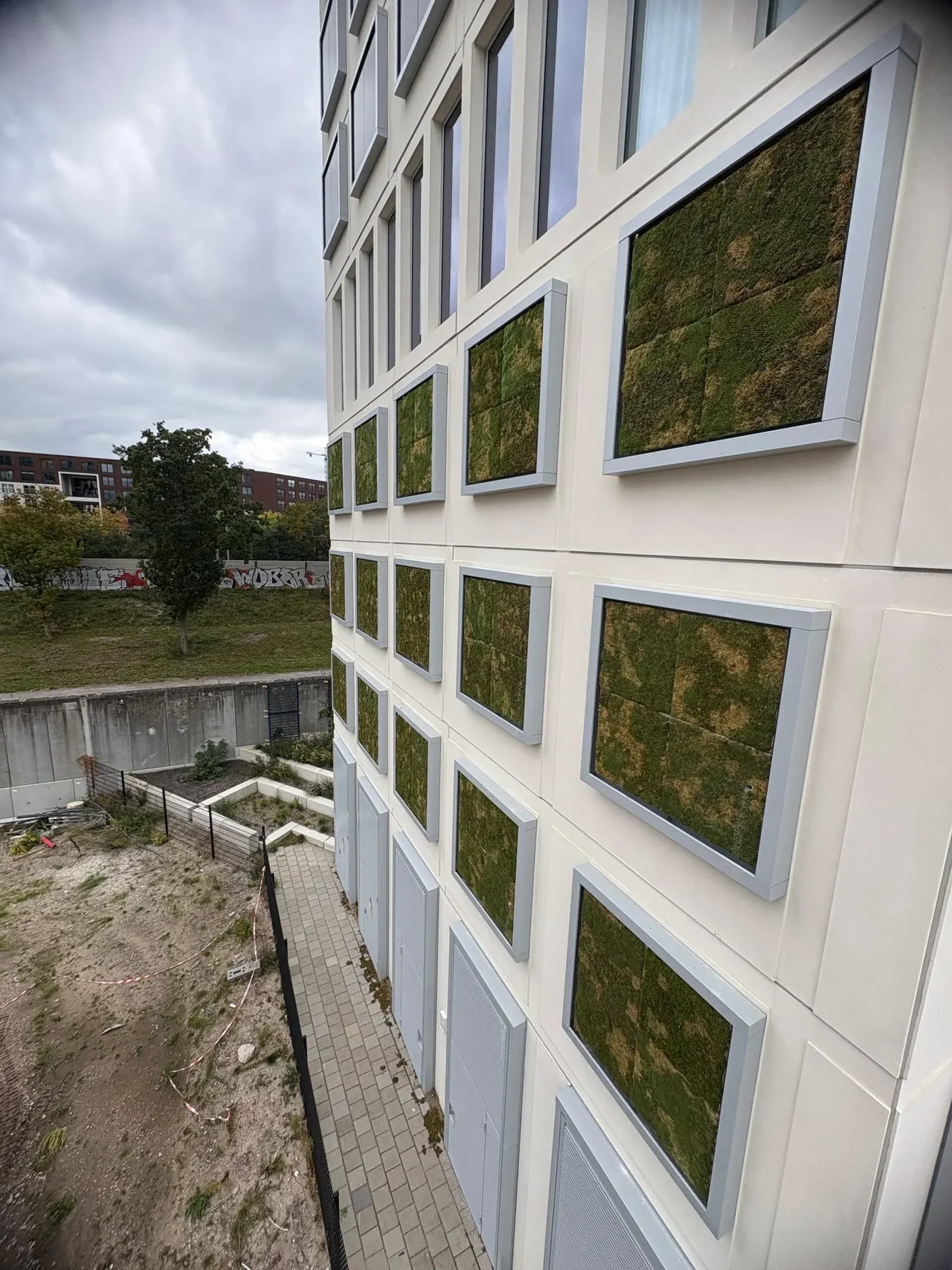 Residential building in Amsterdam with moss panels in gray frames on its facade