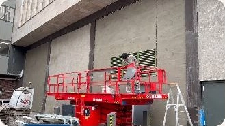 Medewerker op een hoogwerker bij de gevel van het gebouw aan het Spui in Den Haag