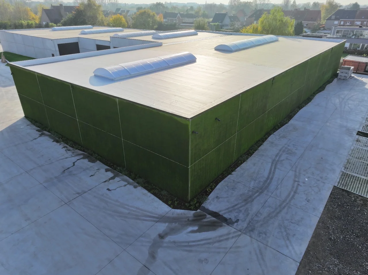 Aerial view of a flat-roofed industrial building with a fully moss-covered facade